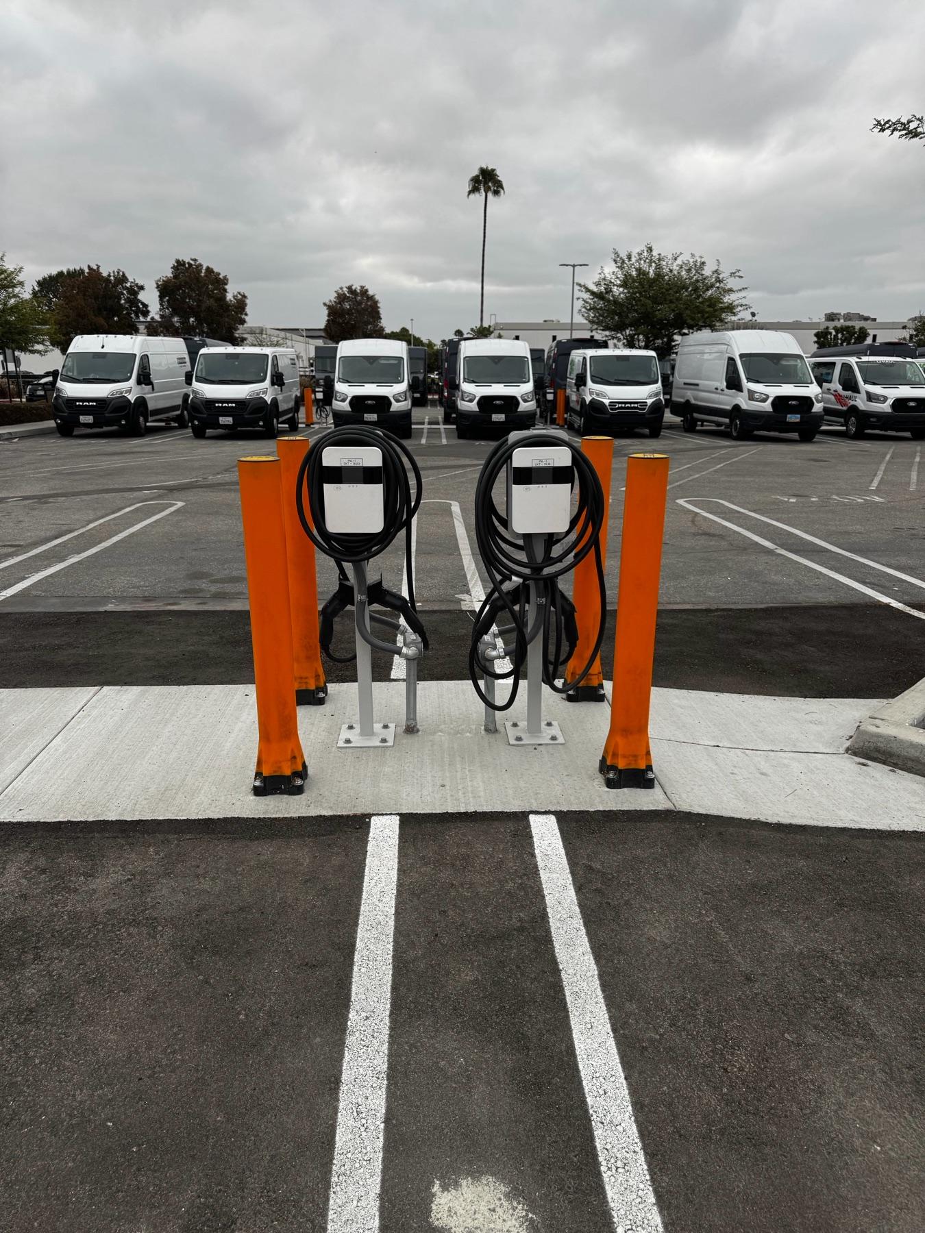 Two pedestal EV chargers with cable management at a fleet lot